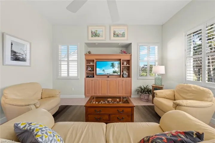 Vaulted ceilings with a central fan, custom light-wood built-in cabinetry, shuttered windows, and tile flooring