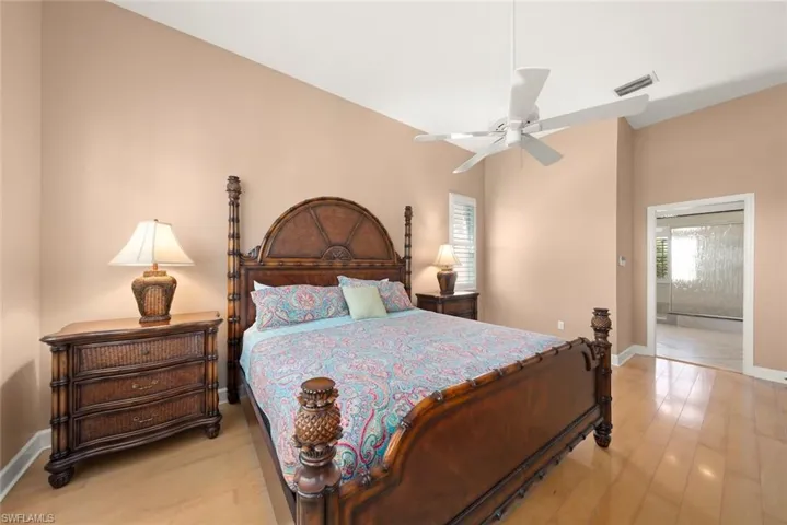 Vaulted ceiling with a white overhead fan, wood-finish flooring, and white plantation shutters