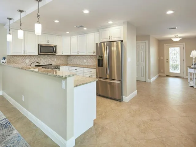 Kitchen features stainless appliances and shaker cabinets.