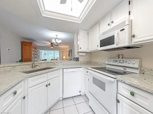Kitchen with white appliances, a sink, a ceiling fan, and white cabinetry