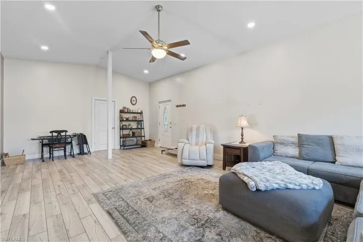 Living area with recessed lighting, ceiling fan, lofted ceiling, and light wood finished floors