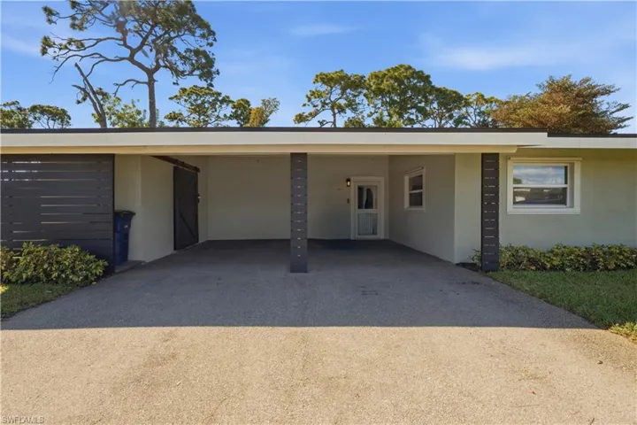 View of front of house with stucco siding, driveway, and a carport