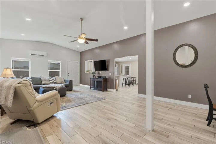 Living area featuring light wood-type flooring, a ceiling fan, recessed lighting, and vaulted ceiling