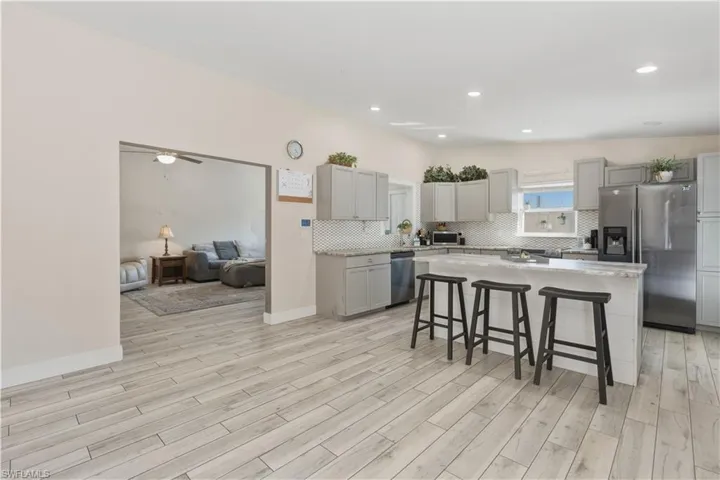 Kitchen featuring a kitchen bar, gray cabinets, stainless steel appliances, a kitchen island, and wood finish floors