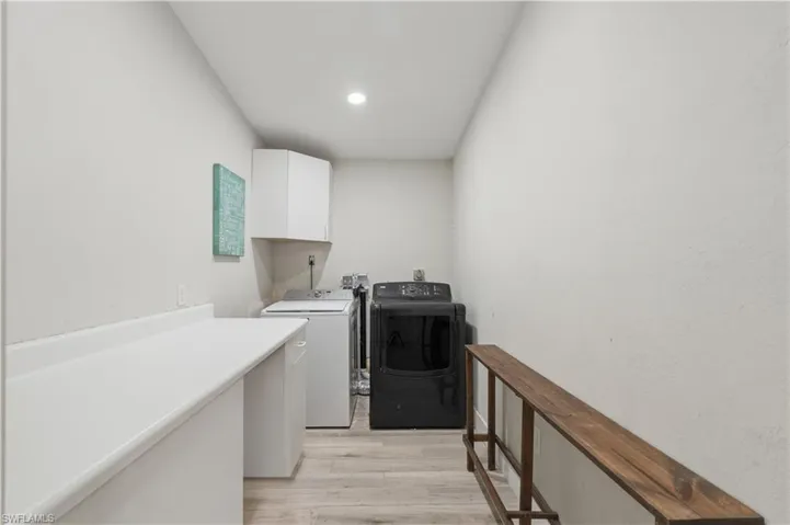 Laundry area with light wood finished floors, independent washer and dryer, cabinet space, and recessed lighting