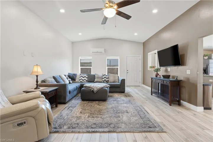 Living room featuring ceiling fan, lofted ceiling, light wood-type flooring, and recessed lighting