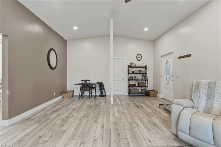 Living area with lofted ceiling, light wood finished floors, recessed lighting, and ceiling fan