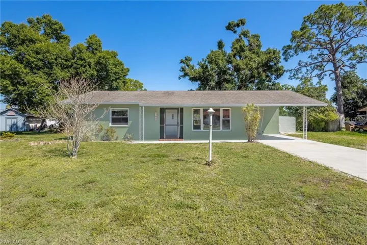Single story home featuring a front yard, stucco siding, driveway, and a carport