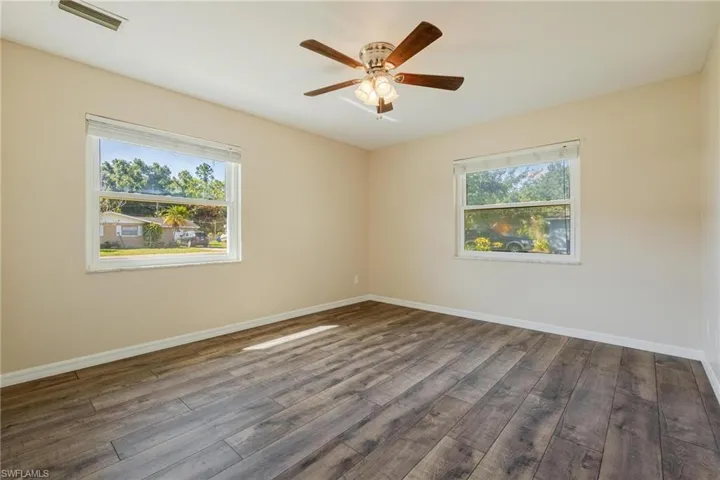 Spare room featuring dark wood-style flooring and ceiling fan