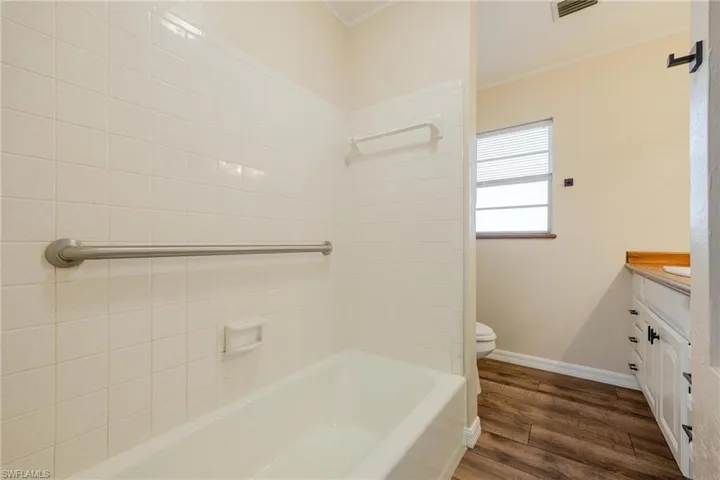 Full bathroom featuring vanity, bathing tub / shower combination, dark wood-type flooring, and crown molding