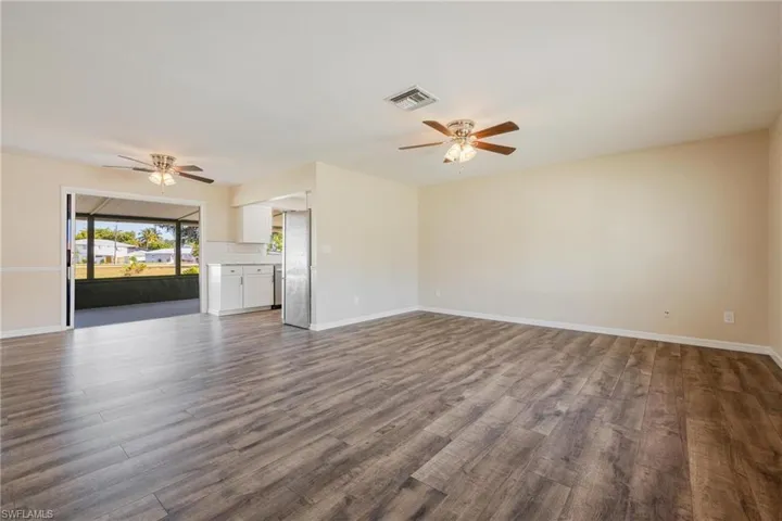 Unfurnished living room featuring ceiling fan and dark wood-style floors