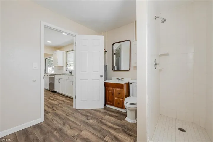 Bathroom with vanity, dark wood finished floors, and tiled shower