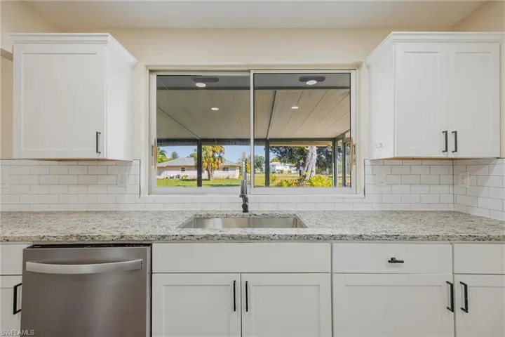 Kitchen with dishwasher, white cabinetry, light stone counters, tasteful backsplash, and recessed lighting