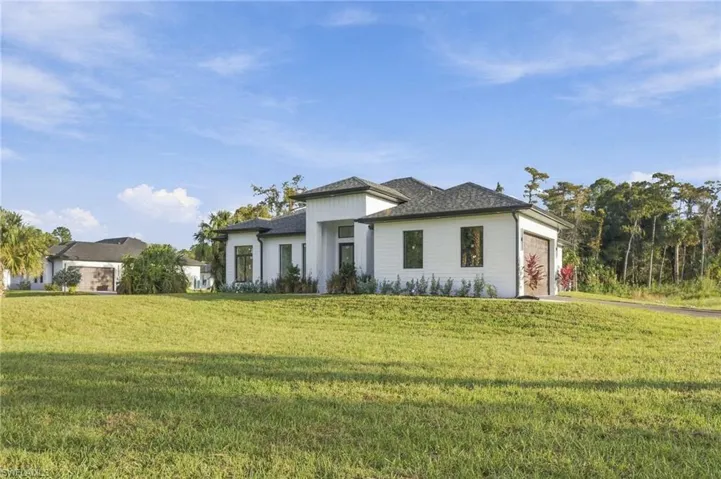 Single-story residence featuring white horizontal siding, a hipped roof, multi-car garage, and expansive lawn area