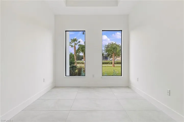 Neutral-toned tile flooring, recessed ceiling detail, and dual floor-to-ceiling windows