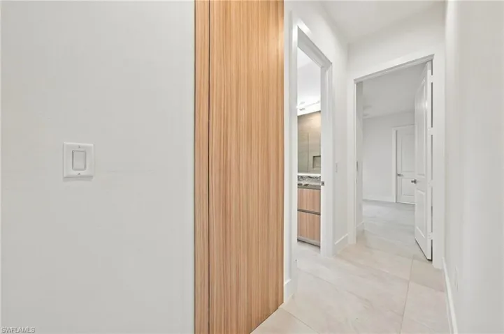 Hallway featuring tile flooring, a floor-to-ceiling wood-finish panel, and white paneled doors