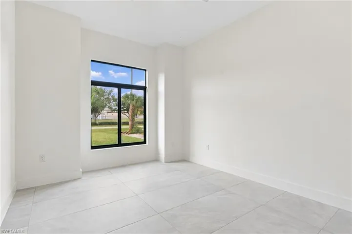 Neutral interior space featuring oversized ceramic tile flooring, a high ceiling, and a large black-framed window