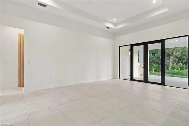 Tray ceiling with recessed lighting, large-format tile flooring, and floor-to-ceiling multi-panel glass doors with black frames