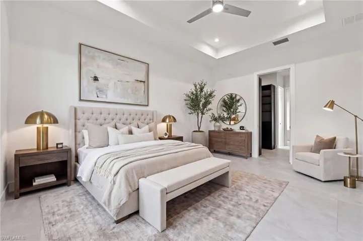 Spacious room featuring a tray ceiling, neutral-toned tile flooring, and a ceiling fan with integrated lighting