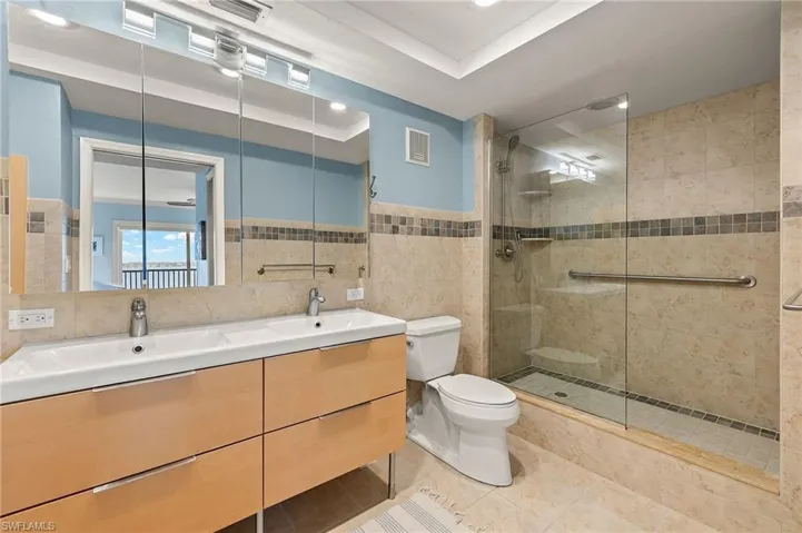 Bathroom with toilet, vanity, tile walls, and tiled shower