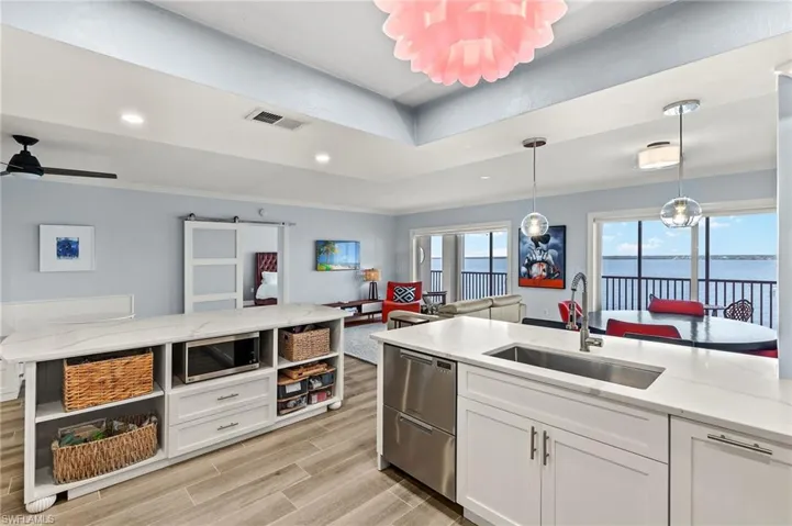 Kitchen with sink, hanging light fixtures, stainless steel appliances, a water view, and white cabinets