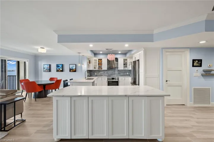 Kitchen featuring decorative light fixtures, light stone counters, white cabinetry, and appliances with stainless steel finishes