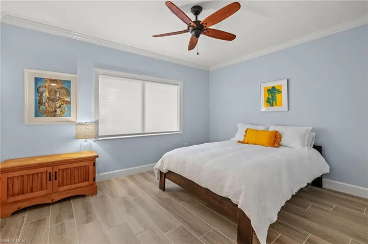 Bedroom with ceiling fan, light hardwood / wood-style flooring, and ornamental molding