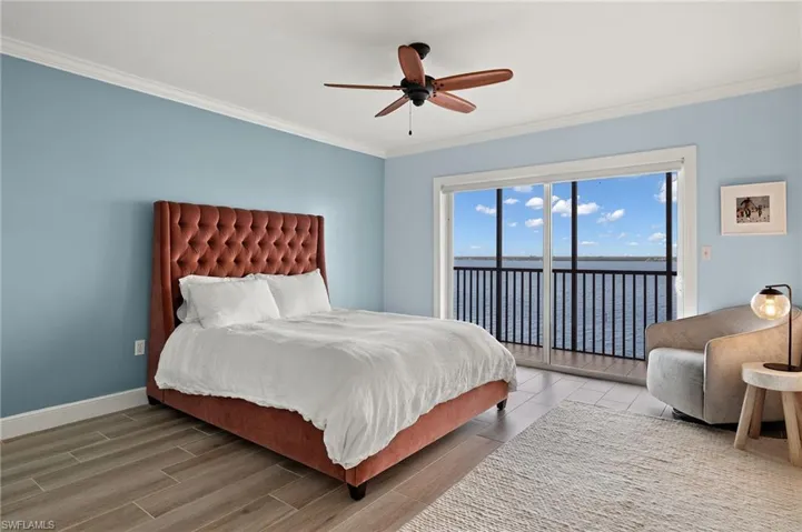 Bedroom featuring access to exterior, a water view, ceiling fan, and ornamental molding