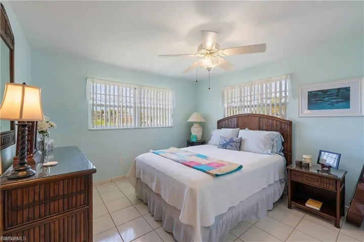 Bedroom featuring multiple windows, light tile patterned floors, and a ceiling fan