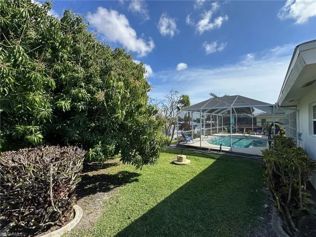 View of green lawn with screened in lanai, and pool patio area