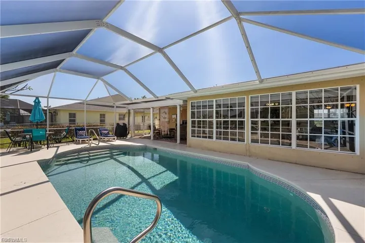 Outdoor pool featuring a sunroom, a patio, and glass enclosure