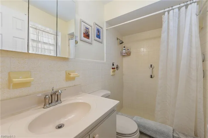 Bathroom featuring tile walls, a stall shower, and vanity