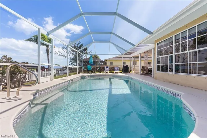 Swimming pool featuring a sunroom, a patio area, glass enclosure, and a grill