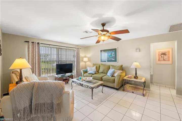 Living room with a ceiling fan and light tile patterned floors