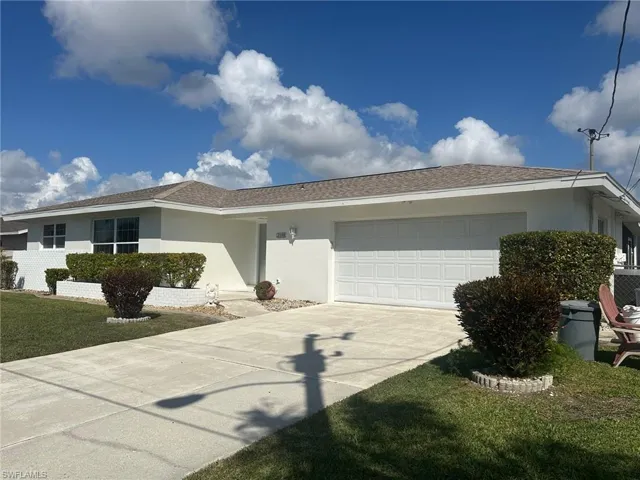 Single story home featuring stucco siding, concrete driveway, a garage, a front lawn, and a shingled roof