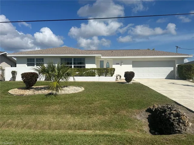 Single story home with concrete driveway, an attached garage, stucco siding, and a front yard