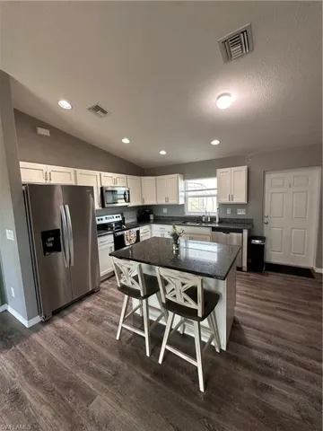 Kitchen featuring stainless steel appliances, quartz countertop, barstool seating at island.  Window and door to backyard.