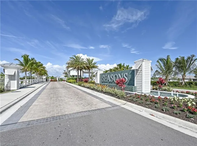 View of asphalt street featuring curbs and a gated entry