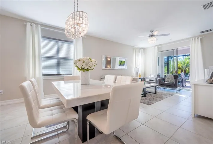 Dining space with light tile patterned floors, ceiling fan, and suspended lighting