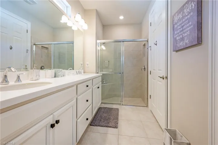 Bathroom with double vanity, light tile patterned floors, a shower stall, and recessed lighting