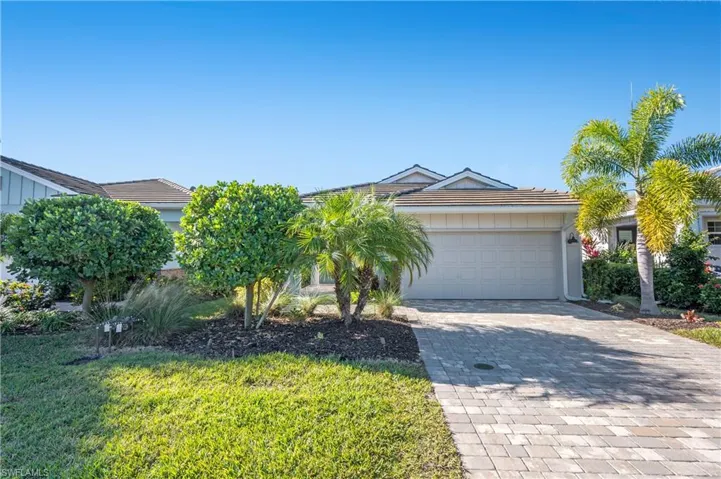 View of front of home featuring decorative driveway, an attached garage, and a front lawn