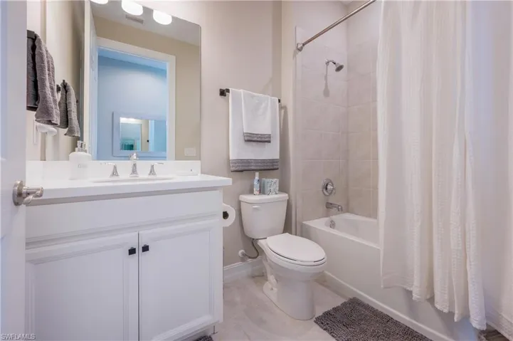Full bath with vanity, shower / tub combo, and light tile patterned flooring