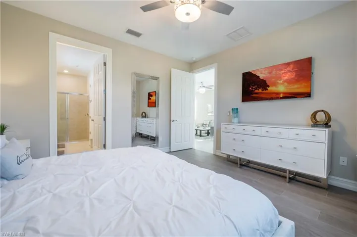 Bedroom with ceiling fan, light wood-type flooring, and connected bathroom