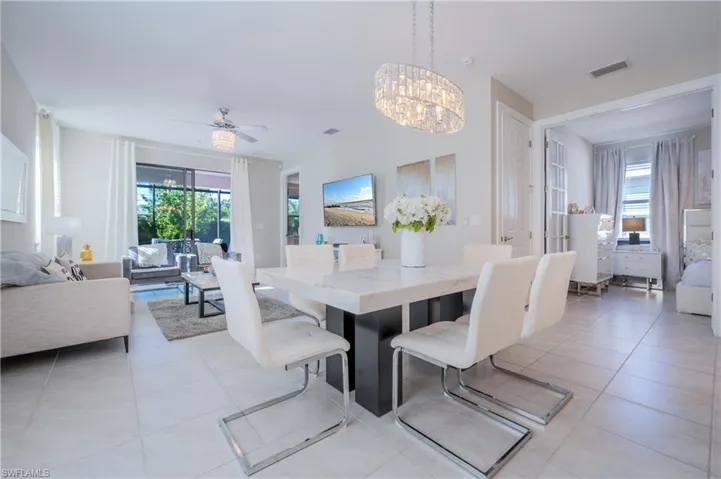Dining space with hanging lights, light tile patterned floors, ceiling fan, and plenty of natural light
