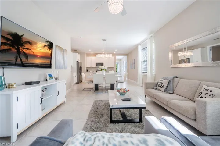 Living room featuring a ceiling fan, a chandelier, and light tile patterned floors