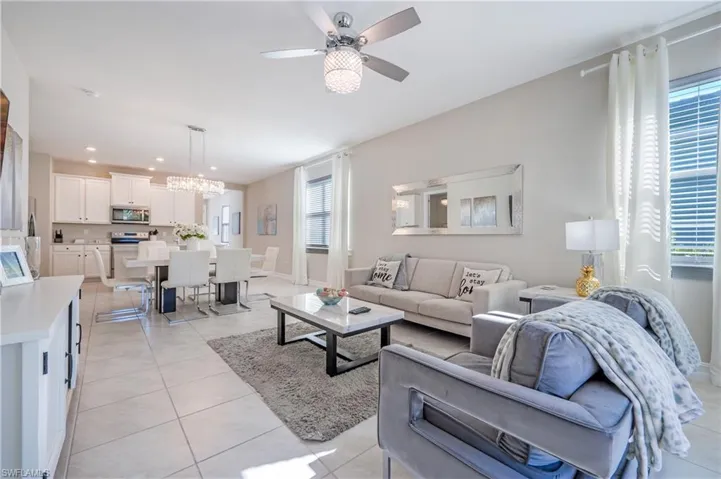 Living area with ceiling fan, suspended lighting, and light tile patterned floors