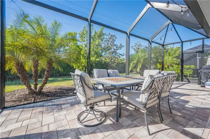 View of patio with glass enclosure, outdoor dining space, a sunroom, and a grill