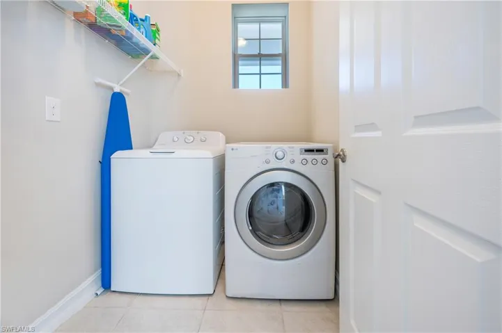 Laundry area with light tile patterned floors and washing machine and dryer