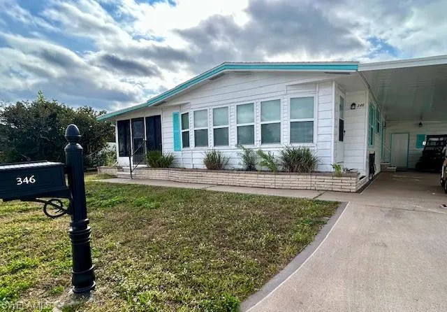 Manufactured / mobile home with a front lawn, a carport, and driveway