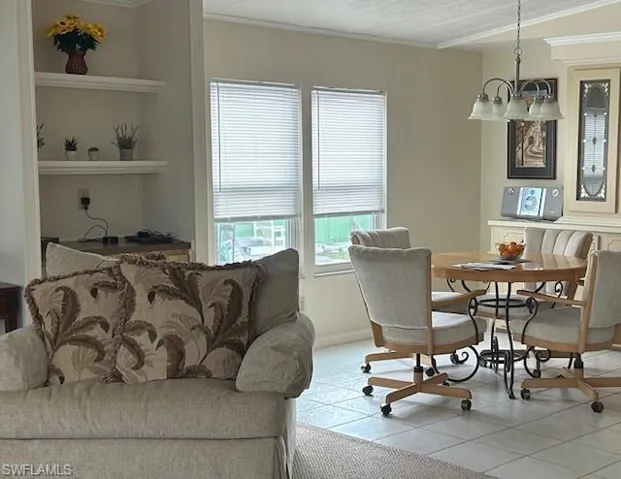 Dining area featuring crown molding, light tile patterned floors, built in shelves, and a chandelier
